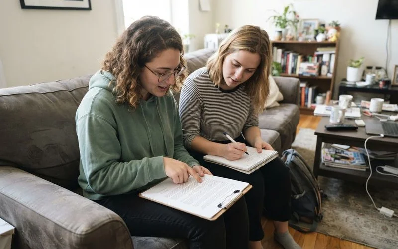 Three roommates reviewing a lease and a separate written roommate agreement together at a table